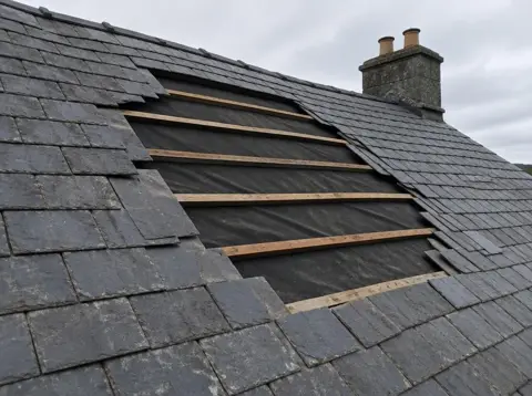 Section of slate roof with missing slates and exposed battens